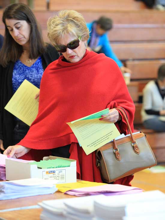 Susie Macrae (left) and Nancy Gustafson pick up literature as they arrive at Town Meeting.