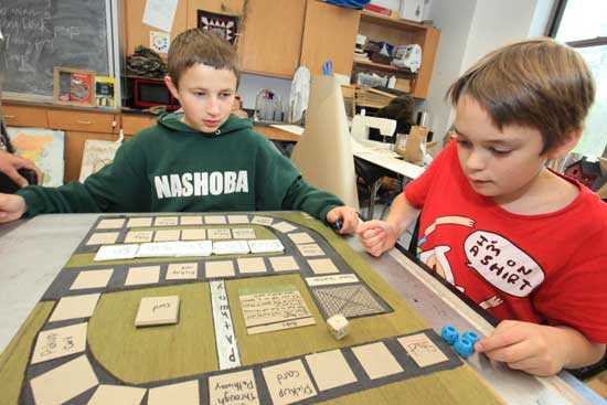 Sixth-graders Matthew Alfieri (left) and Jack Sorgi play a round of “Dogs and Found,” a board game they developed about homeless animals. The sixth grade was tasked with designing a game about a social problem they were concerned about.