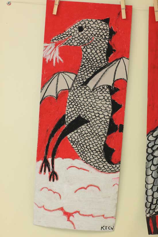   A drawing of a dragon in back, white, and red pastel media.